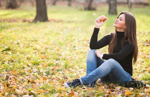 Porträt einer schönen jungen Frau mit Apfel im Herbstpark — Stockfoto