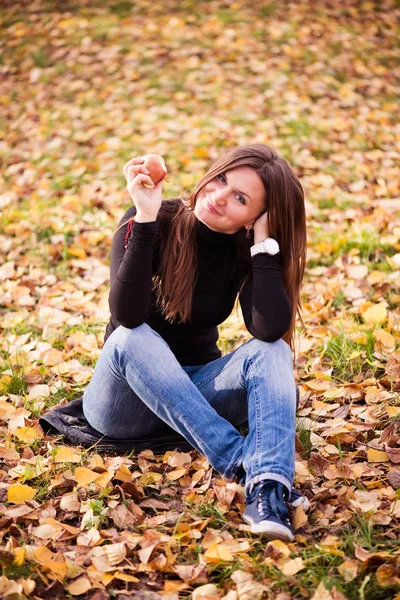Portrait of beautiful young woman with apple in autumn park — Stock Photo, Image