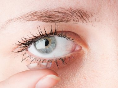 Close up of inserting a contact lens in female eye clipart