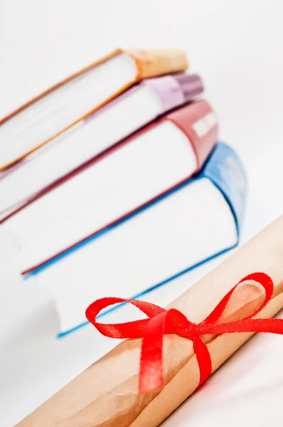 Diploma met rood lint en boeken — Stockfoto