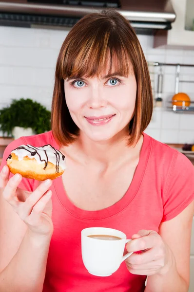 Ung kvinna njuter av en kopp kaffe och munk — Stockfoto