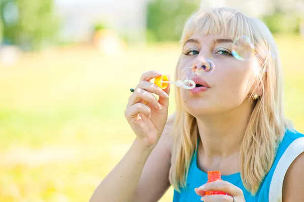 Woman blowing bubbles in park — Stock Photo, Image