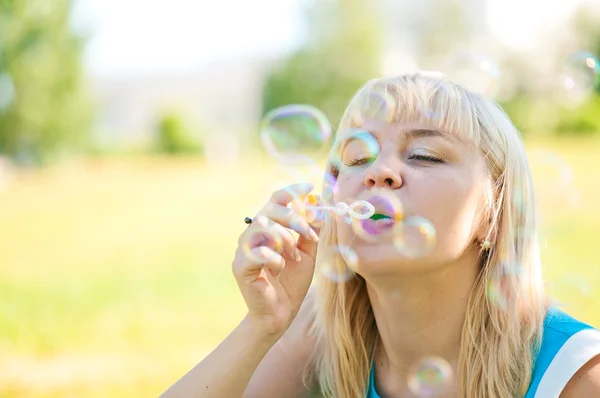 Vrouw waait bubbels in park — Stockfoto