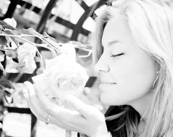 Mujer joven y bonita oliendo una rosa — Foto de Stock