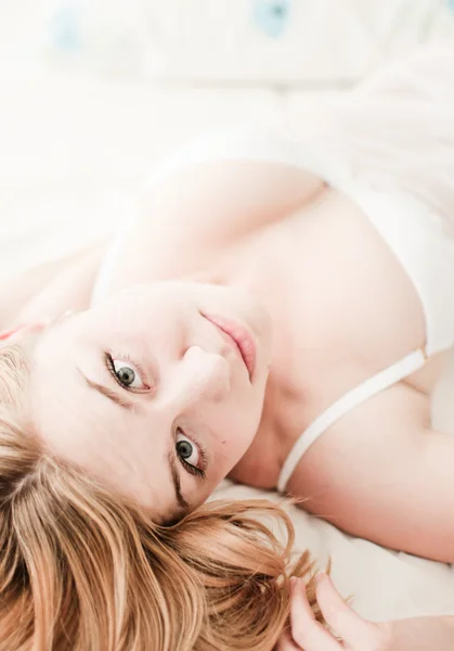 Mulher loira sexy deitada na cama em lingerie Imagem De Stock