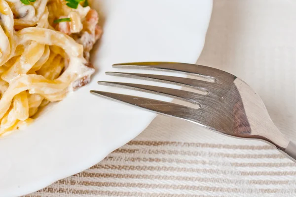 Espaguetis. Fettuccine carbonara en un bol blanco, adornado con tocino, champiñones y perejil — Foto de Stock