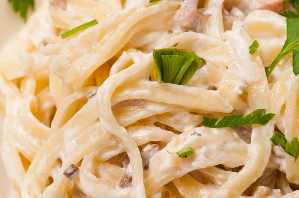 Spagettia. Fettuccine carbonara valkoisessa kulhossa, koristeltu pekonilla, sienillä ja persiljalla — kuvapankkivalokuva