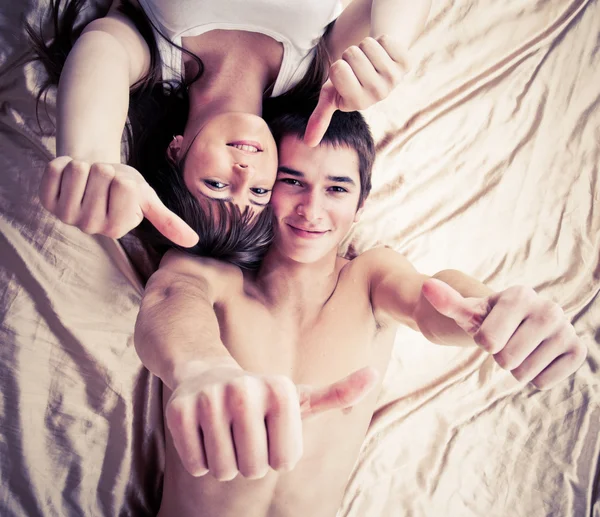 親指でベッドに横たわっている幸せなカップル — ストック写真