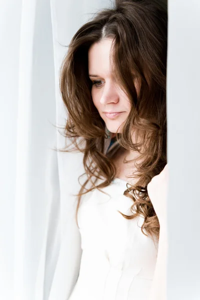 Attractive young adult looking at the window with serious look — Stock Photo, Image