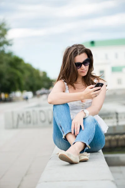 Utomhus porträtt av ung kvinna med telefonen Stockbild