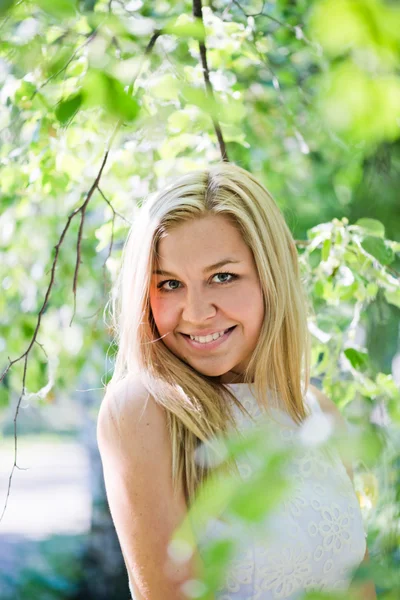 Mooie jonge blonde vrouw in een wit kleed buitenshuis — Stockfoto