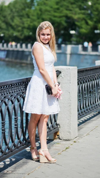 Mooie jonge blonde vrouw in een wit kleed buitenshuis — Stockfoto