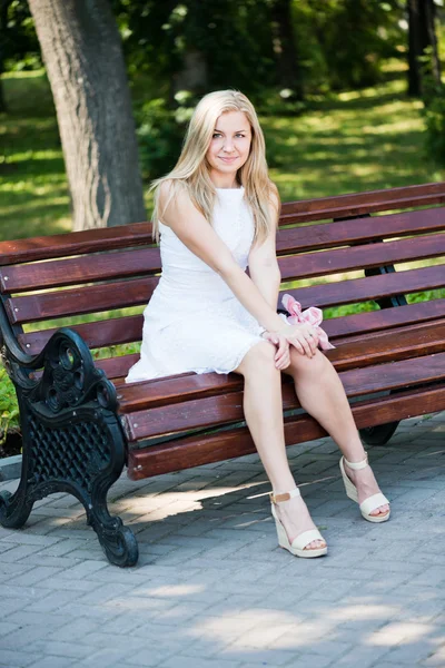 Jeune femme assise sur le banc dans le parc — Photo