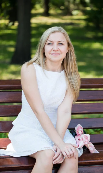 Young woman sitting on the bench in park — Stock Photo, Image