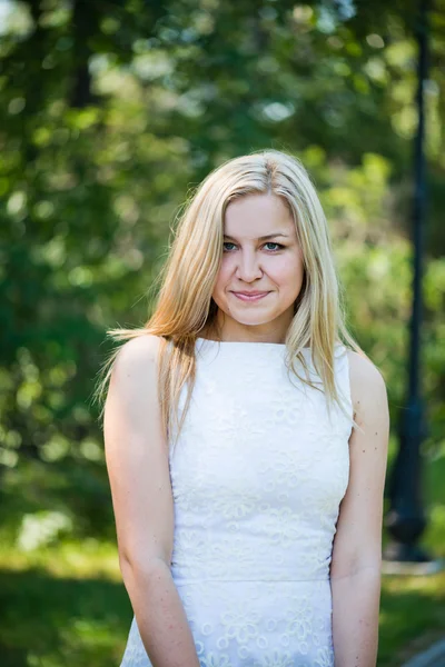 Mooie jonge blonde vrouw in een wit kleed buitenshuis — Stockfoto