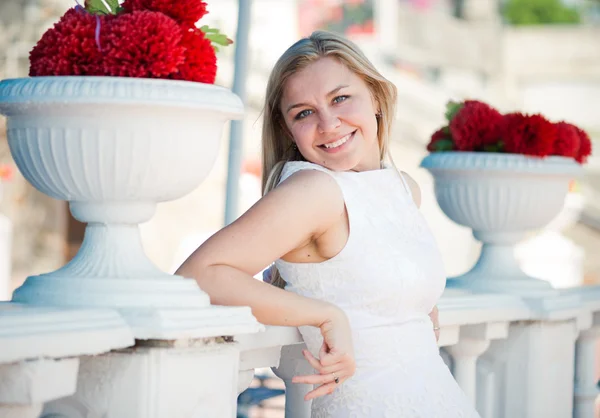 Beautiful european woman near red flowers in white vases — Stock Photo, Image