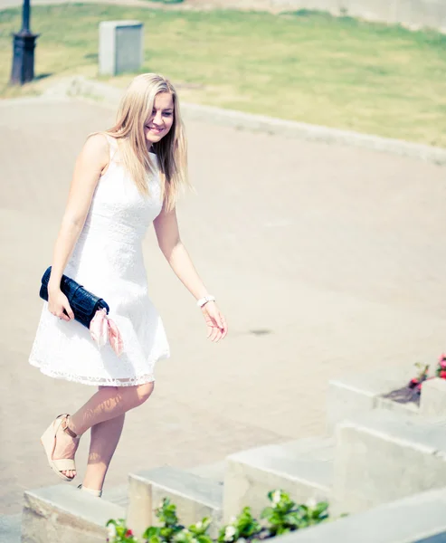 Beautiful blond woman walking upstairs outdoors — Stock Photo, Image