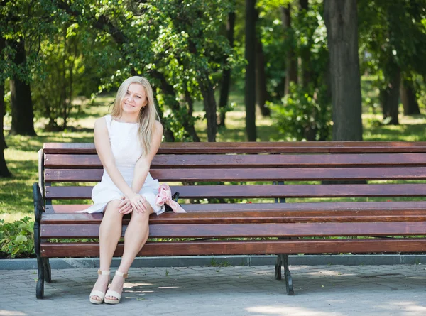 Mujer joven sentada en el banco en el parque — Foto de Stock