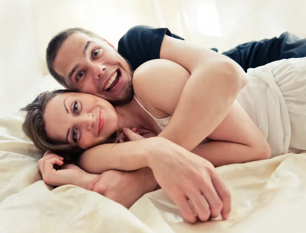 Schönes Paar, das sich zu Hause auf dem Bett umarmt — Stockfoto
