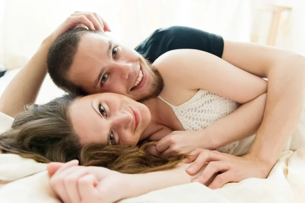 Adorável casal abraçando em sua cama em casa — Fotografia de Stock