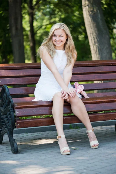 Jeune femme assise sur le banc dans le parc — Photo