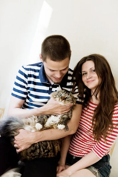 Happy young couple at home with their cat — Stock Photo, Image
