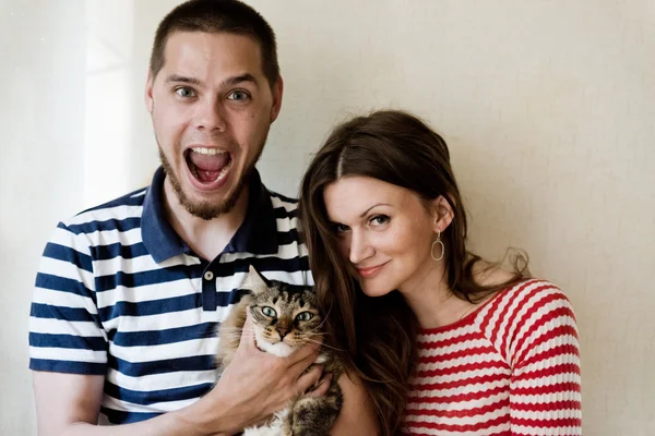 Счастливая молодая пара дома со своим котом — стоковое фото