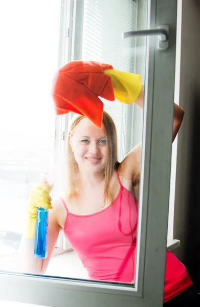 Glad ung kvinna hemmafru tvättar ett fönster — Stockfoto