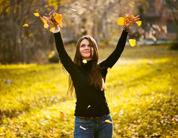 Junge Frau wirft Blätter in den Wald — Stockfoto