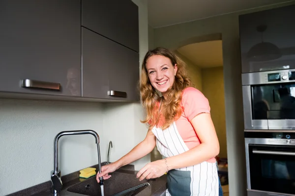 Glückliche junge Frau spült Tasse. Küche. Spülmaschine. — Stockfoto
