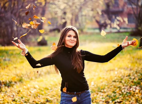 Jeune femme jetant des feuilles femme dans la forêt — Photo