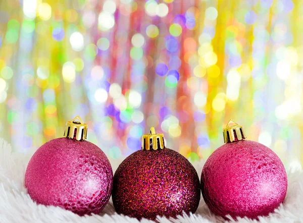 Christmas balls on white fur and colorful lights — Stock Photo, Image