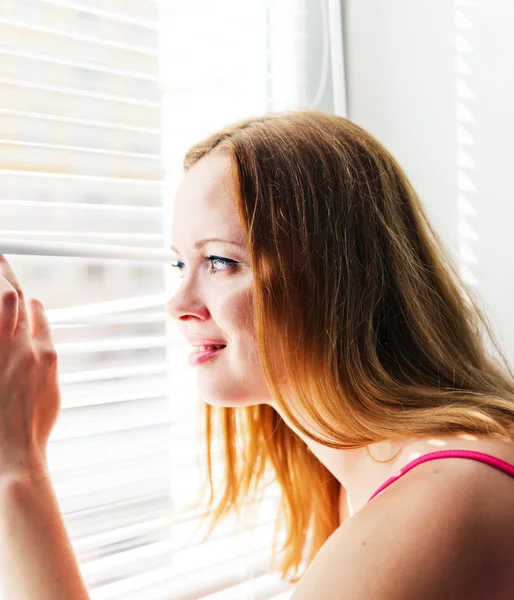 Woman looking out through venison blinds — Stock Photo, Image