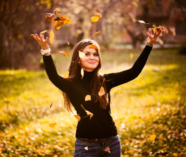 Mujer joven tirando hojas mujer en el bosque —  Fotos de Stock