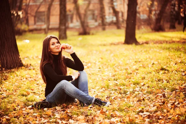 Portret van mooie jonge vrouw met apple in herfst park Stockfoto