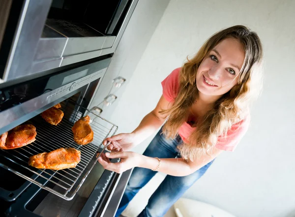 Vacker kvinna sätta kött i ugn — Stockfoto