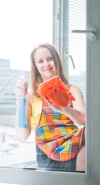 Jovem mulher feliz dona de casa lava uma janela — Fotografia de Stock