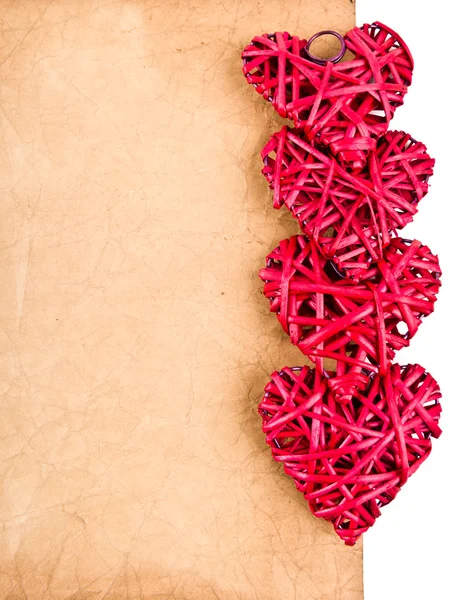 Red straw hearts on old paper — Stock Photo, Image