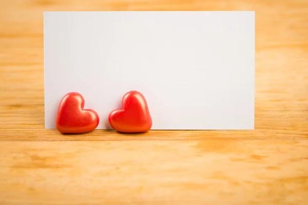 Red hearts and note on wooden background — Stock Photo, Image