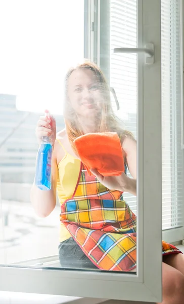 Jovem mulher feliz dona de casa lava uma janela — Fotografia de Stock