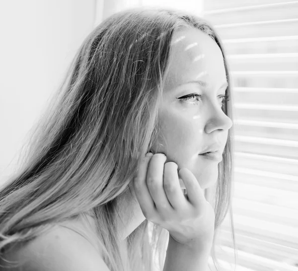 Beautiful woman looking out through venison blinds — Stock Photo, Image