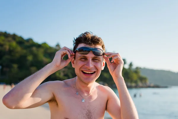 Bello giovane uomo sorridente sulla spiaggia . — Foto Stock
