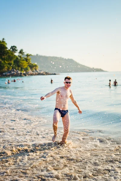 Happy man in the tropical sea with splashes — Stock Photo, Image