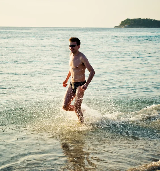 Uomo che corre nell'acqua del mare tropicale — Foto Stock