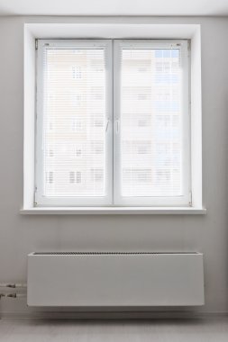 Radyatör altındaki beyaz plastik çift kapı pencere. 