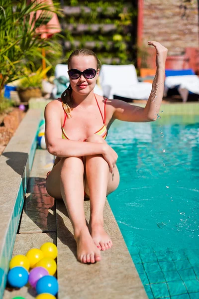 Jonge gelukkig vrouw zitten dicht bij zwembad — Stockfoto