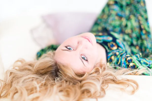 Beautiful young blonde woman with long hair smiling and lying — Stock Photo, Image