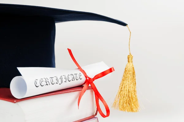 Graduation cap with book and diploma — Stock Photo, Image