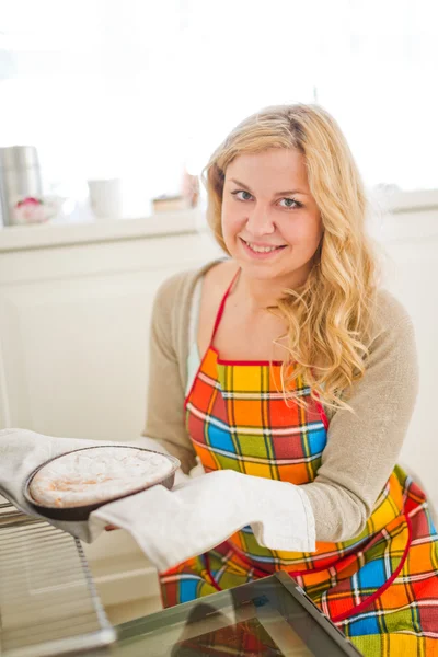 Frau zieht Kuchen aus Ofen — Stockfoto