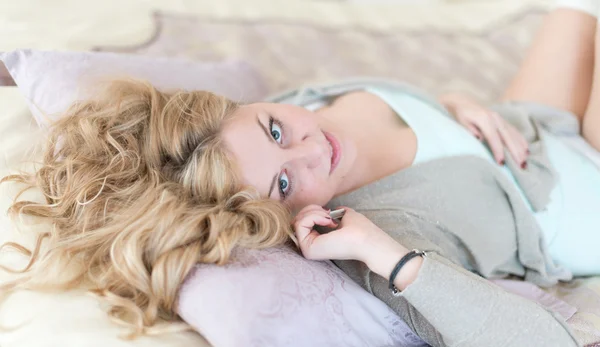 Rubia alegre natural acostada en la cama y llamando por teléfono — Foto de Stock